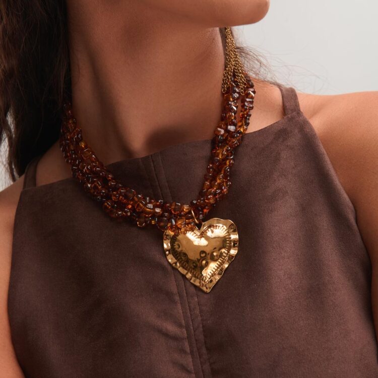 Μοντέλο φοράει το κολιέ Kexribari FunkDaQueen με κεχριμπαρένιες χάντρες και χρυσό ατσάλινο μενταγιόν σε σχήμα καρδιάς