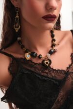 Μοντέλο φοράει το κολιέ Charmheart FunkDaQueen με μαύρες χάντρες, μάτι και χρυσές καρδιές από ρητίνη