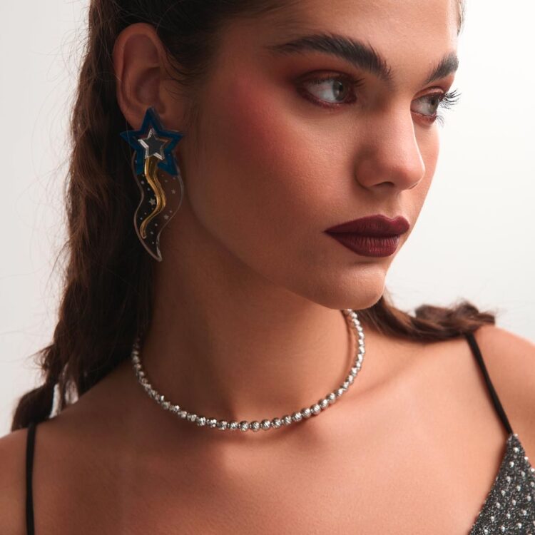 Μοντέλο φοράει τα σκουλαρίκια Starflow από plexiglass σε ασημί και χρυσό, με σχέδιο πεφταστέρι, δημιουργία της FunkDaQueen.