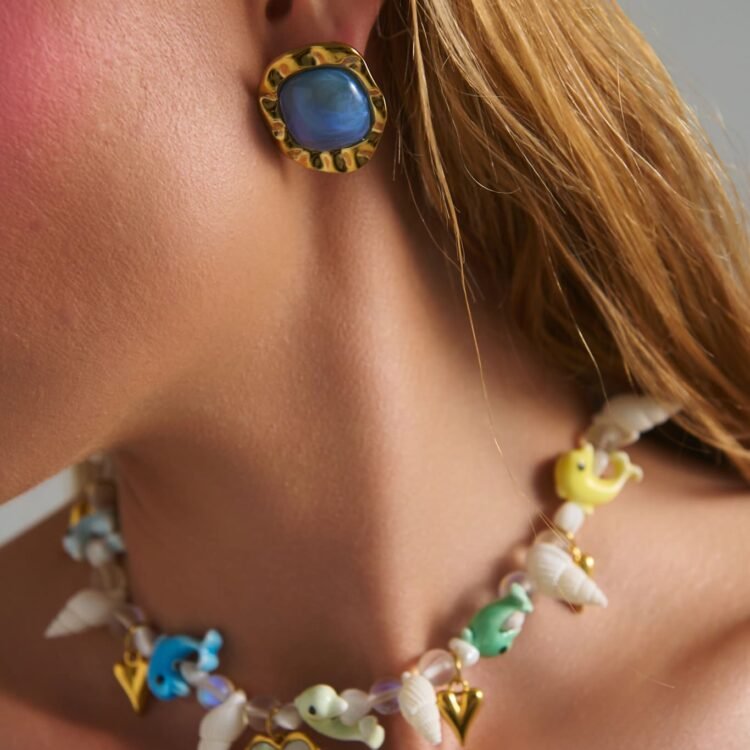 Model wearing Cobalt Blue Earrings with deep blue stone and hammered gold frame