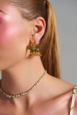 Γυναικείο μοντέλο που φορά τα Flora Hoops χρυσά σκουλαρίκια λουλούδι από ανοξείδωτο ατσάλι