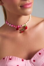 Γυναικείο μοντέλο που φορά το χειροποίητο Cherry Flirt necklace με κεράσια, καρδιά και strawberry charms