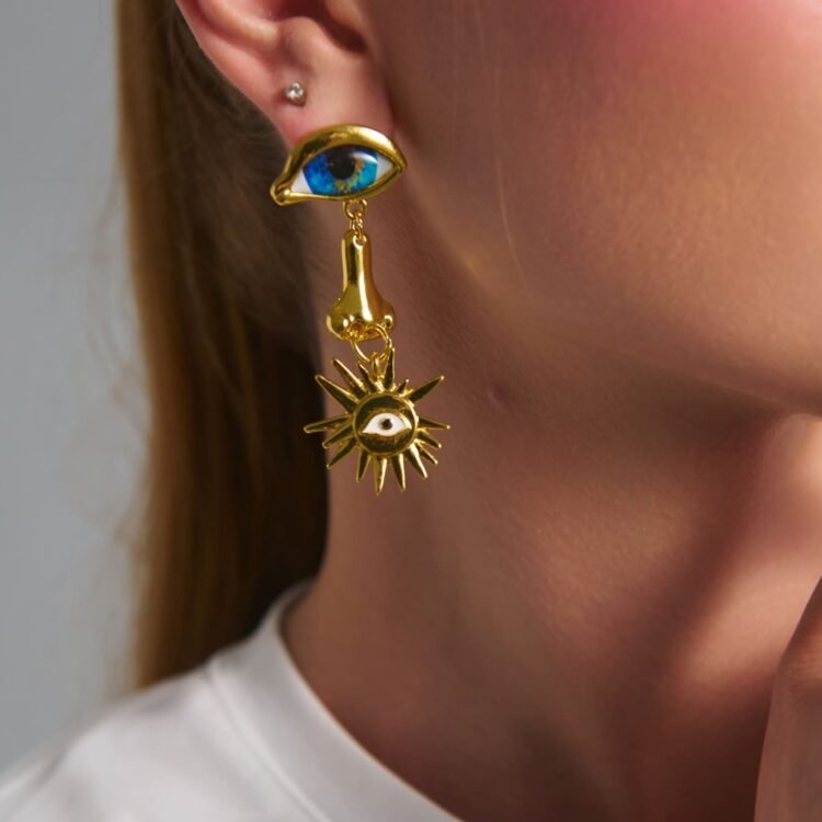 Model wearing Helios Eye Earrings with blue eye detail and gold celestial charm